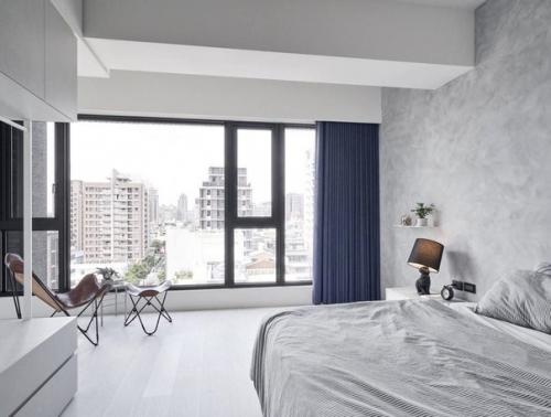 Минималистическая серо - белая спальная, в которую теплый тон привносят стул Komal Handicrafts, подставка для ног и настольная лампа кролик Moooi.