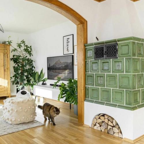 Хороший спокойный интерьер: зелёная печь и тёплые акценты, белые стены, деревянная отделка и обилие зеленых растений. 07