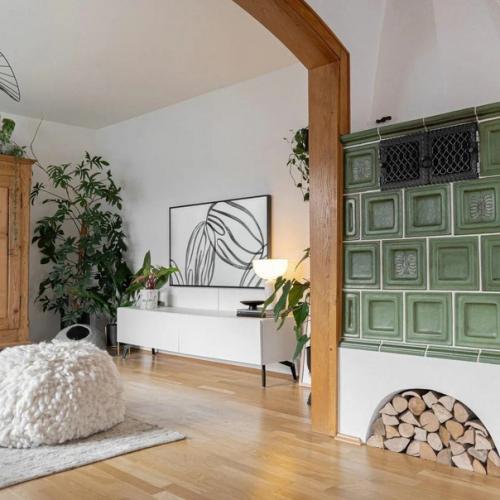 Хороший спокойный интерьер: зелёная печь и тёплые акценты, белые стены, деревянная отделка и обилие зеленых растений. 08