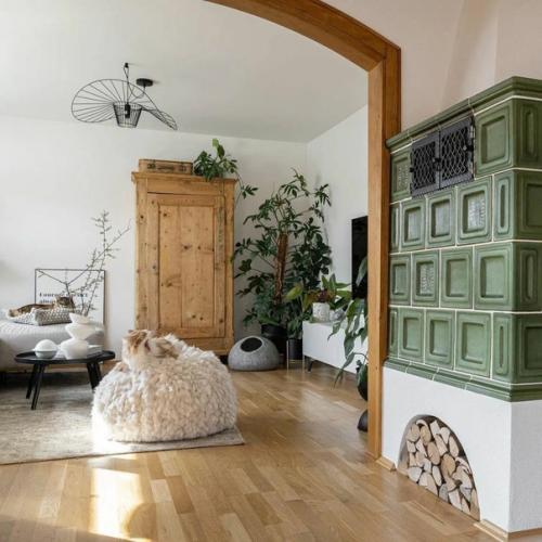 Хороший спокойный интерьер: зелёная печь и тёплые акценты, белые стены, деревянная отделка и обилие зеленых растений. 01